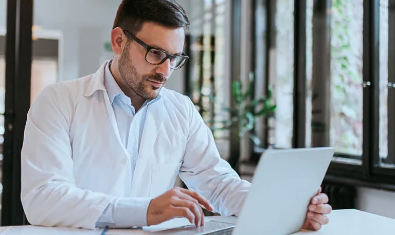 A doctor reading something on a laptop