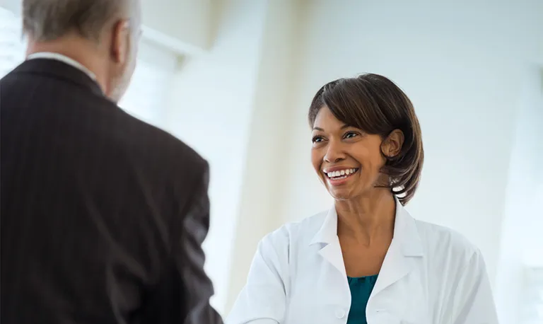 A doctor smiling while talking with a patient